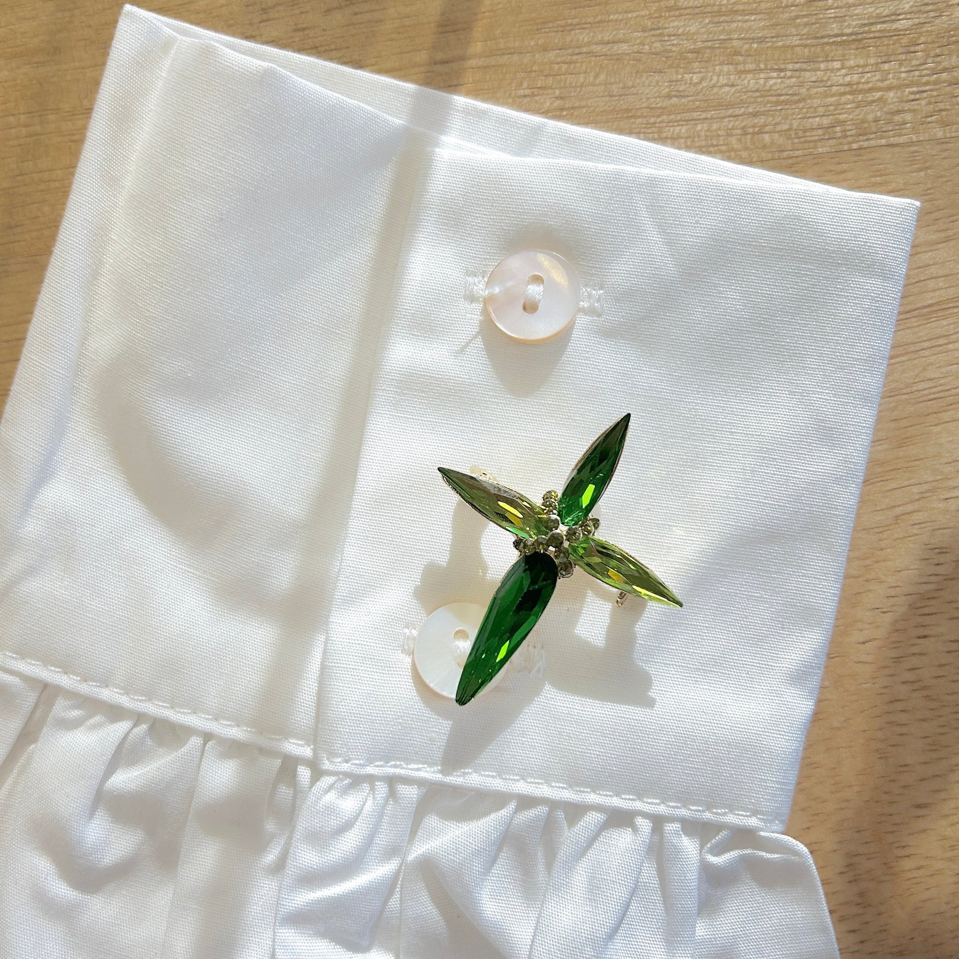 Détail broche croix verte strass