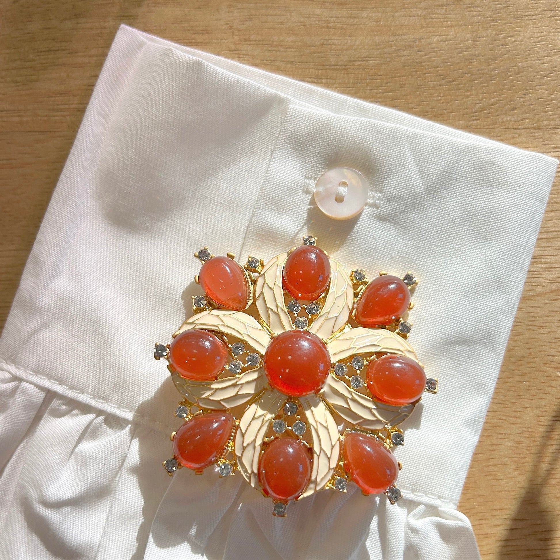 Détail broche fleur corail monture dorée et strass
