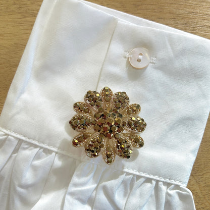 Détail broche fleur dorée strass