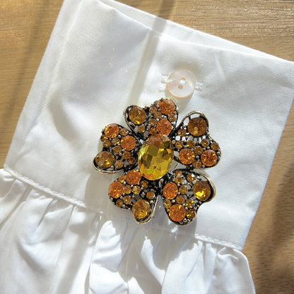 Détail broche fleur orange strass