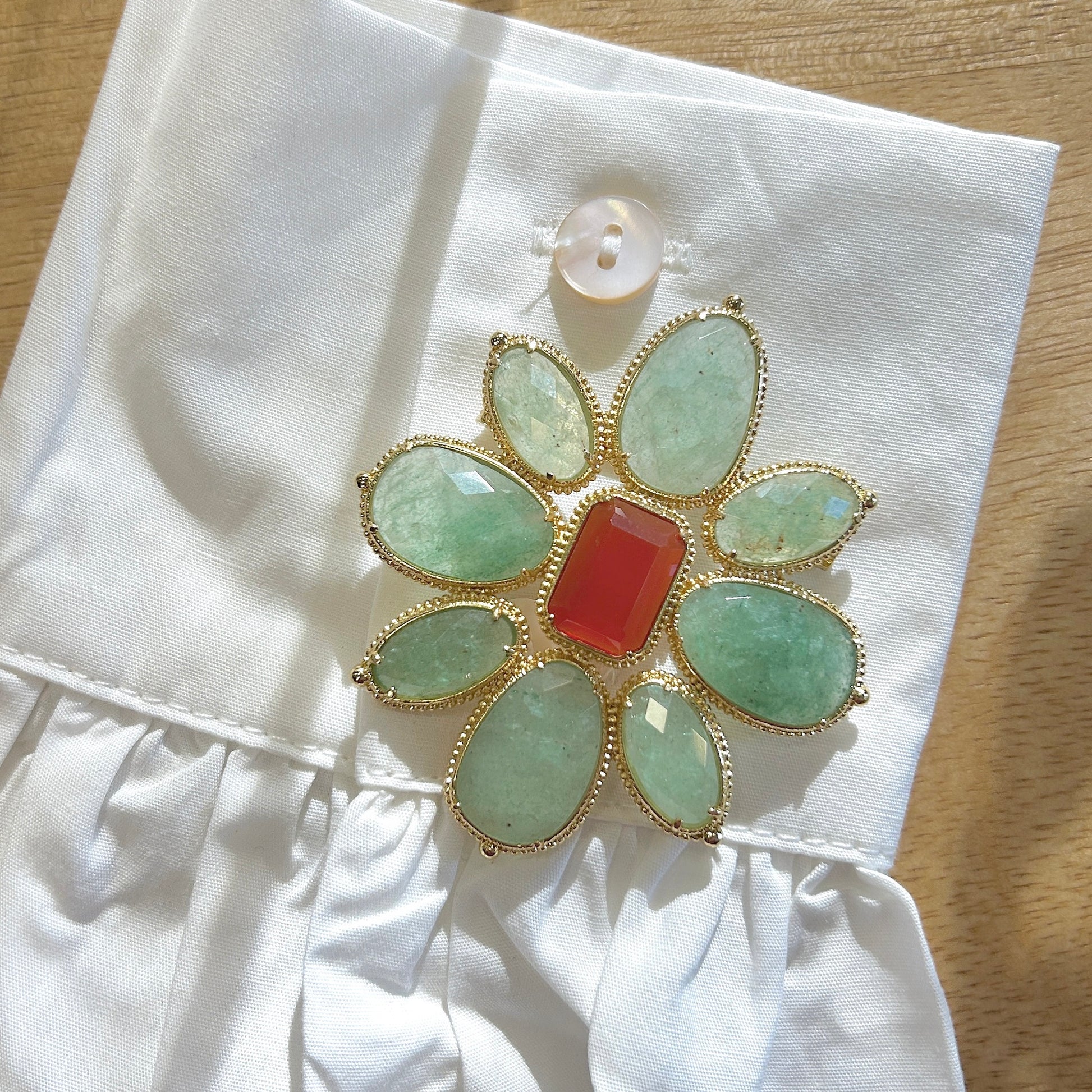 Détail broche fleur verte monture dorée perlée