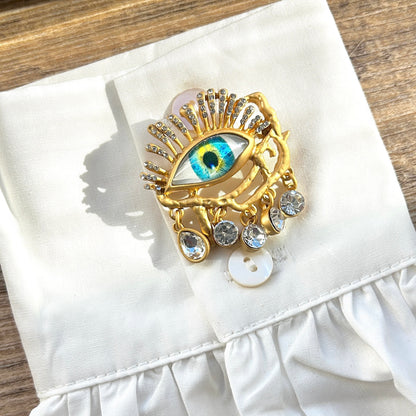 Détail broche œil doré pampilles