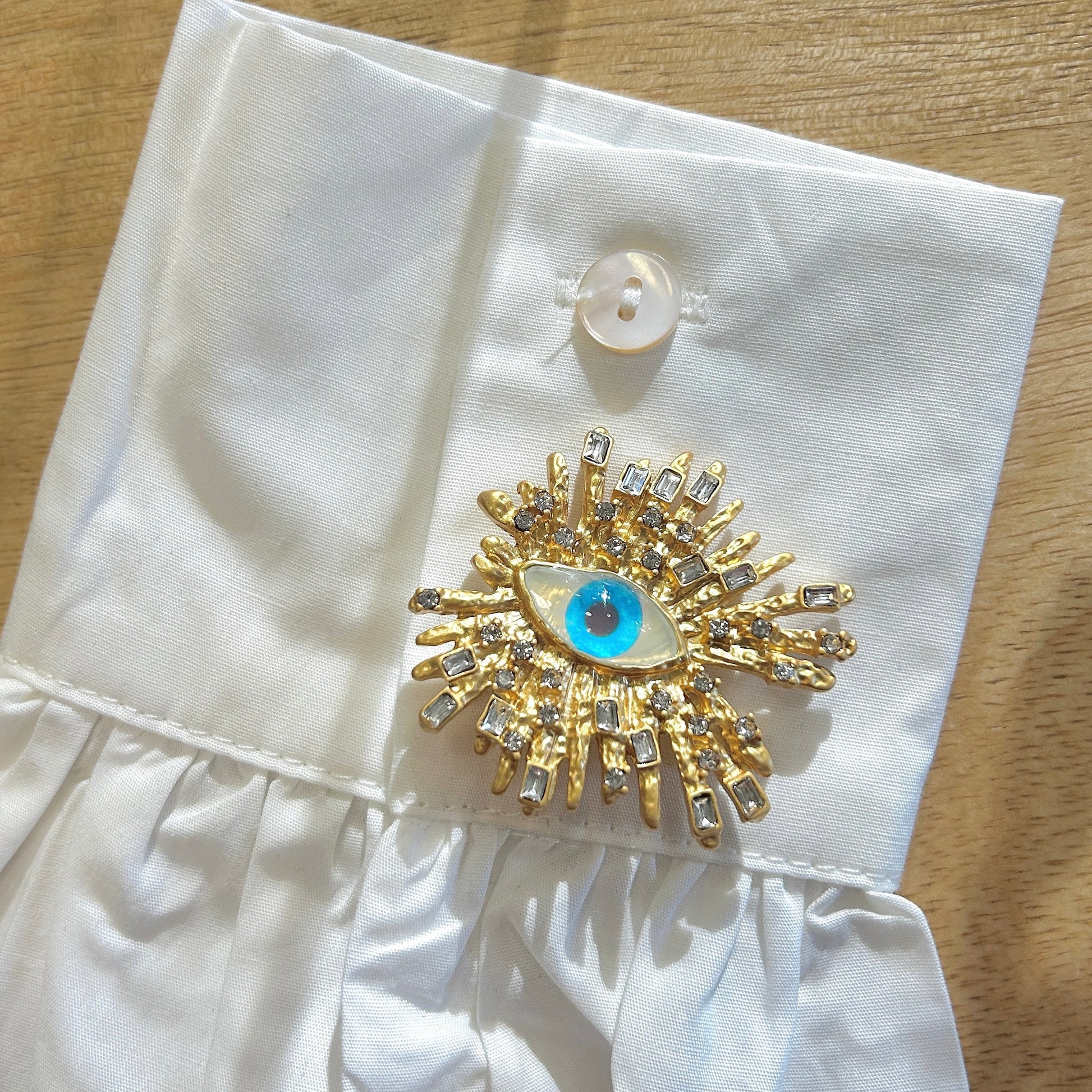 Détail broche œil soleil doré strass