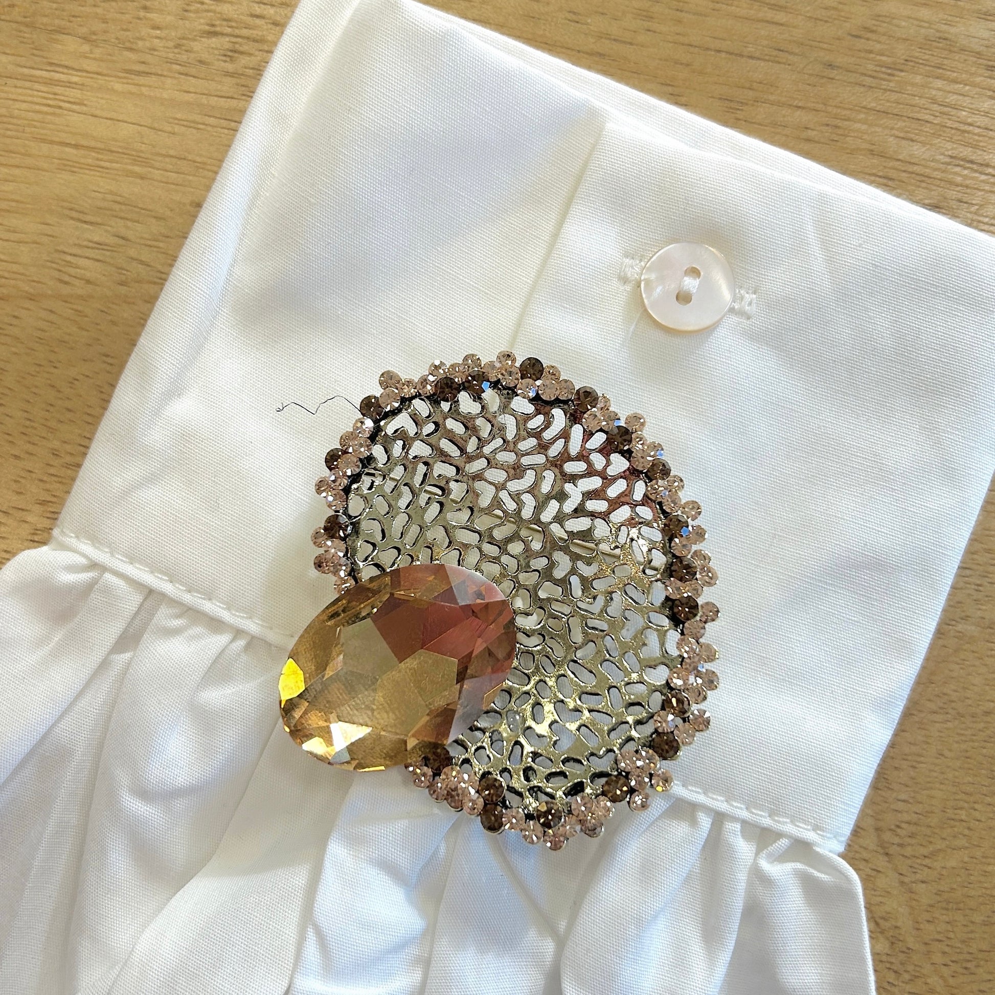 Détail broche ovale dentelle dorée strass