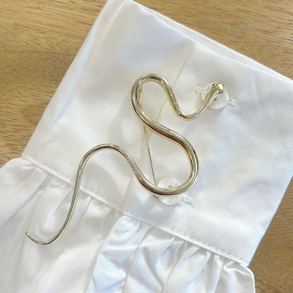 Détail broche serpent doré métal lisse