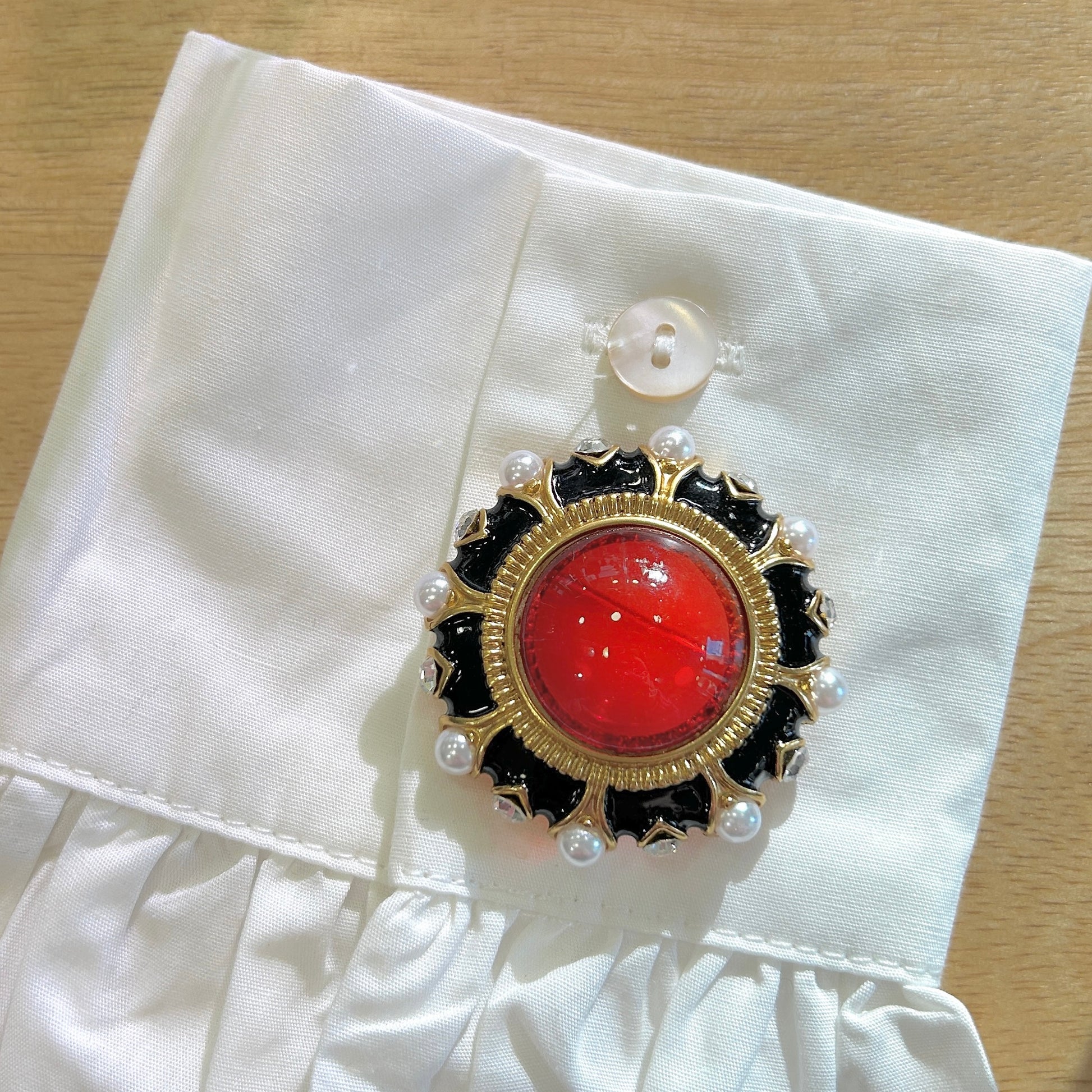 Détail broche cabochon rouge émail noir et perles