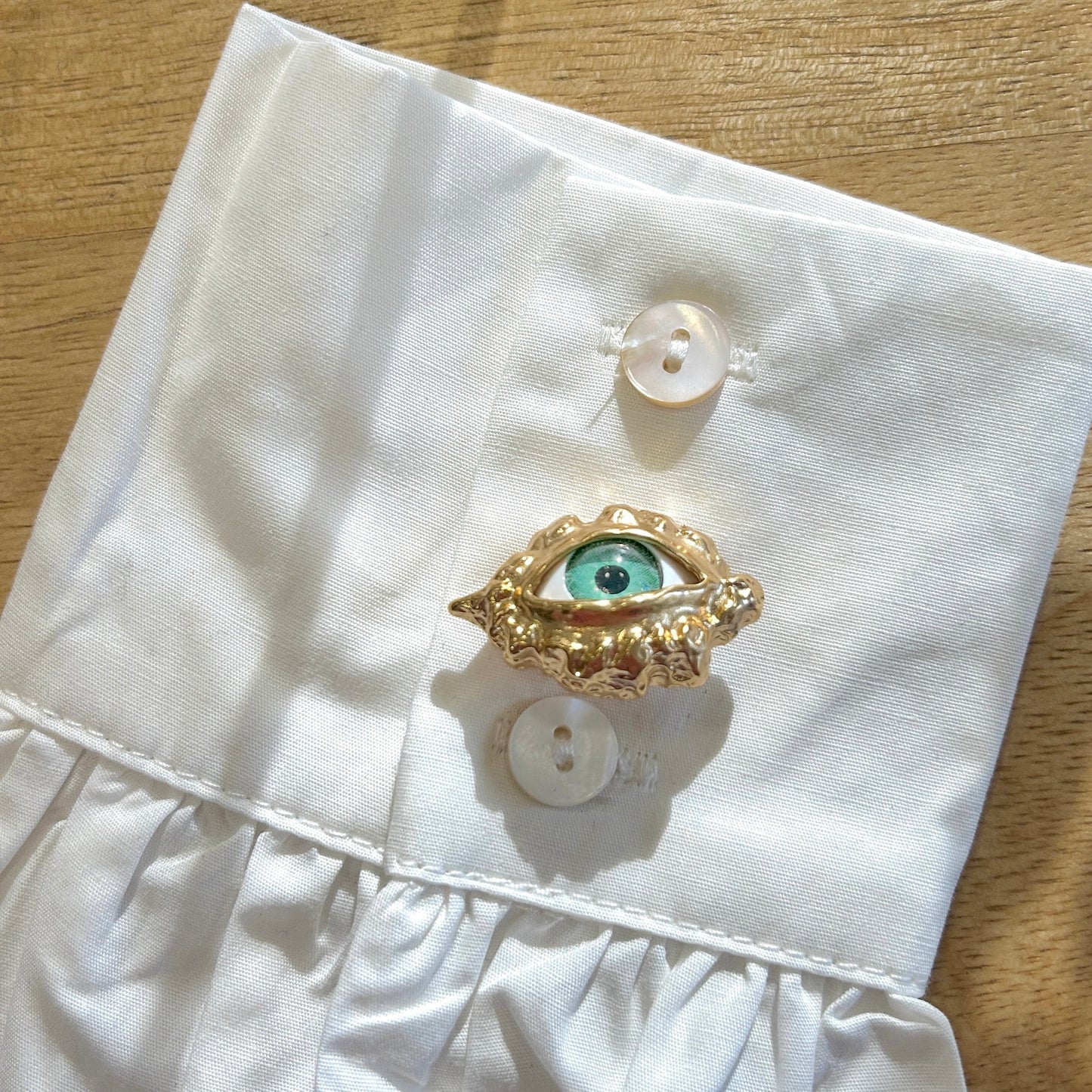Détail broche œil vert dorée