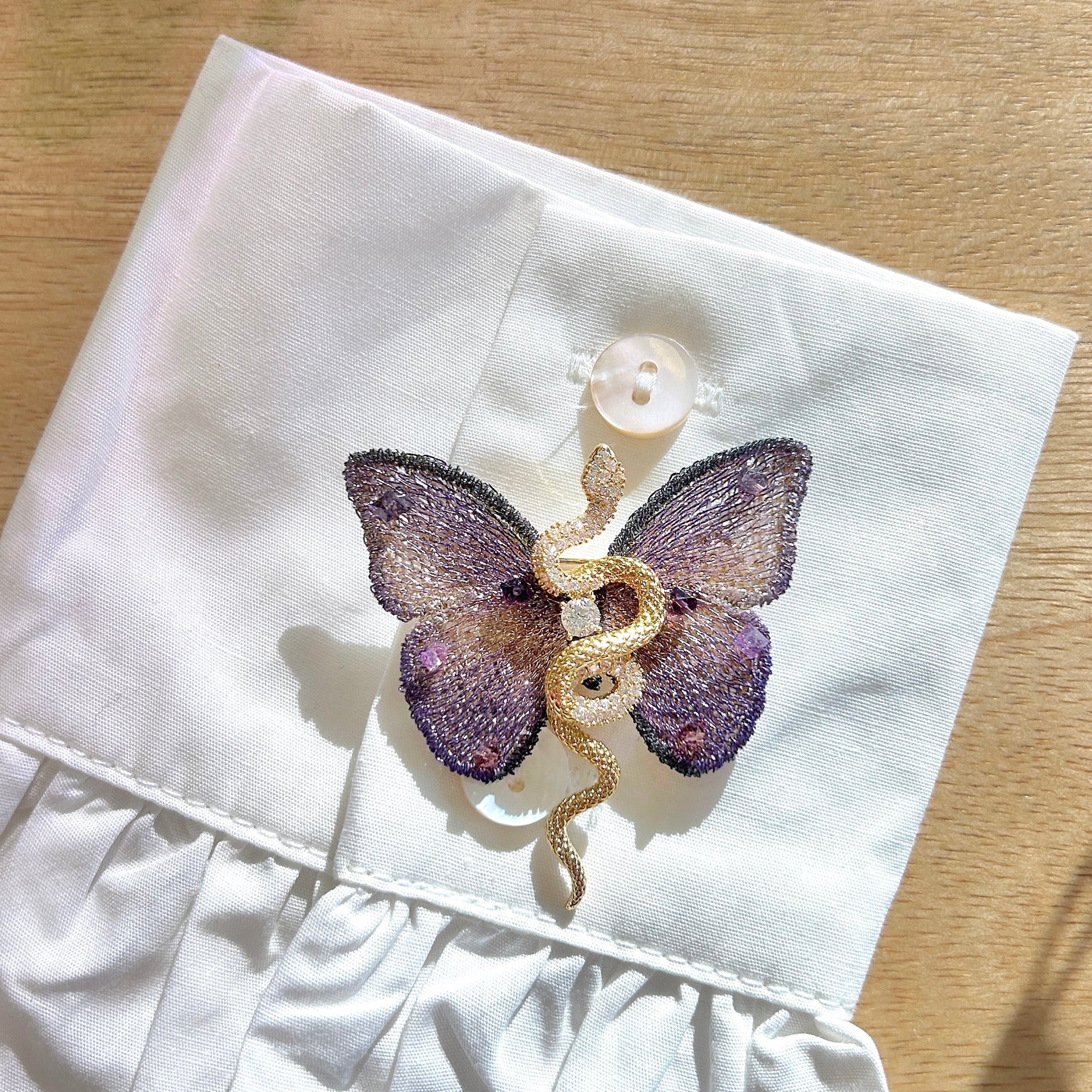 Détail de la broche papillon violet avec serpent doré