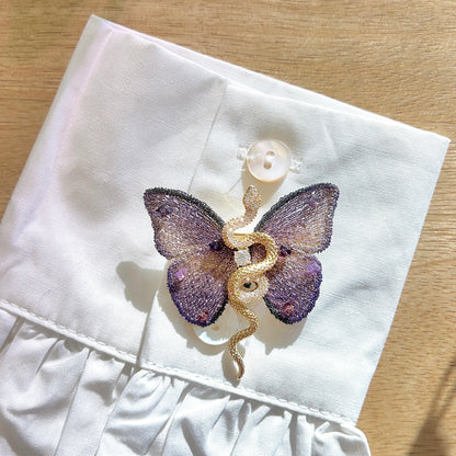 Détail de la broche papillon violet avec serpent doré