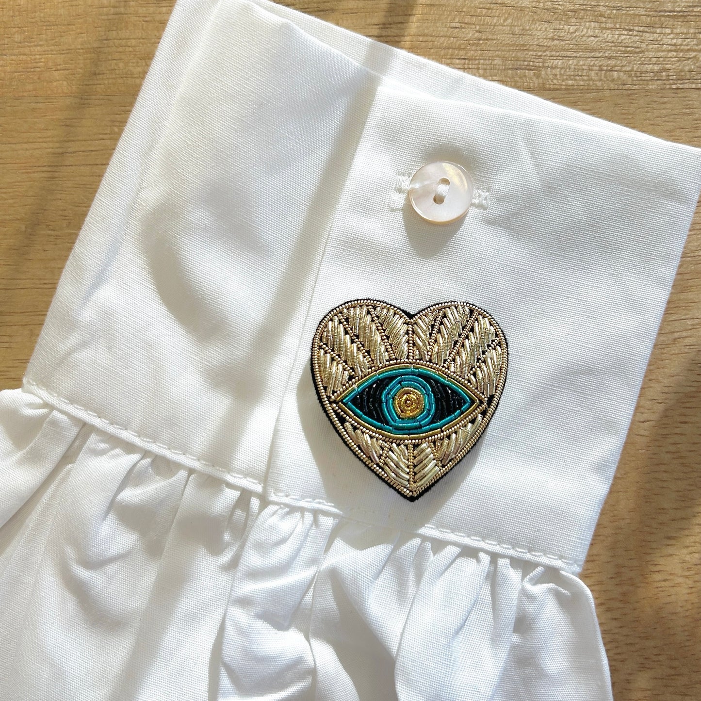 Détail broche tissu cœur œil bleu broderie