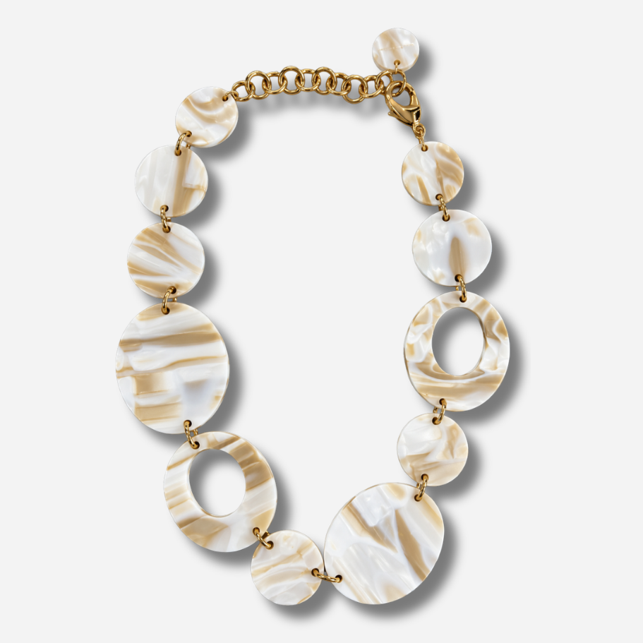 Collier Alba Francine Bramli Paris composé de médaillons ronds marbrés blanc nacré et beige, alternant formes pleines et anneaux ajourés.