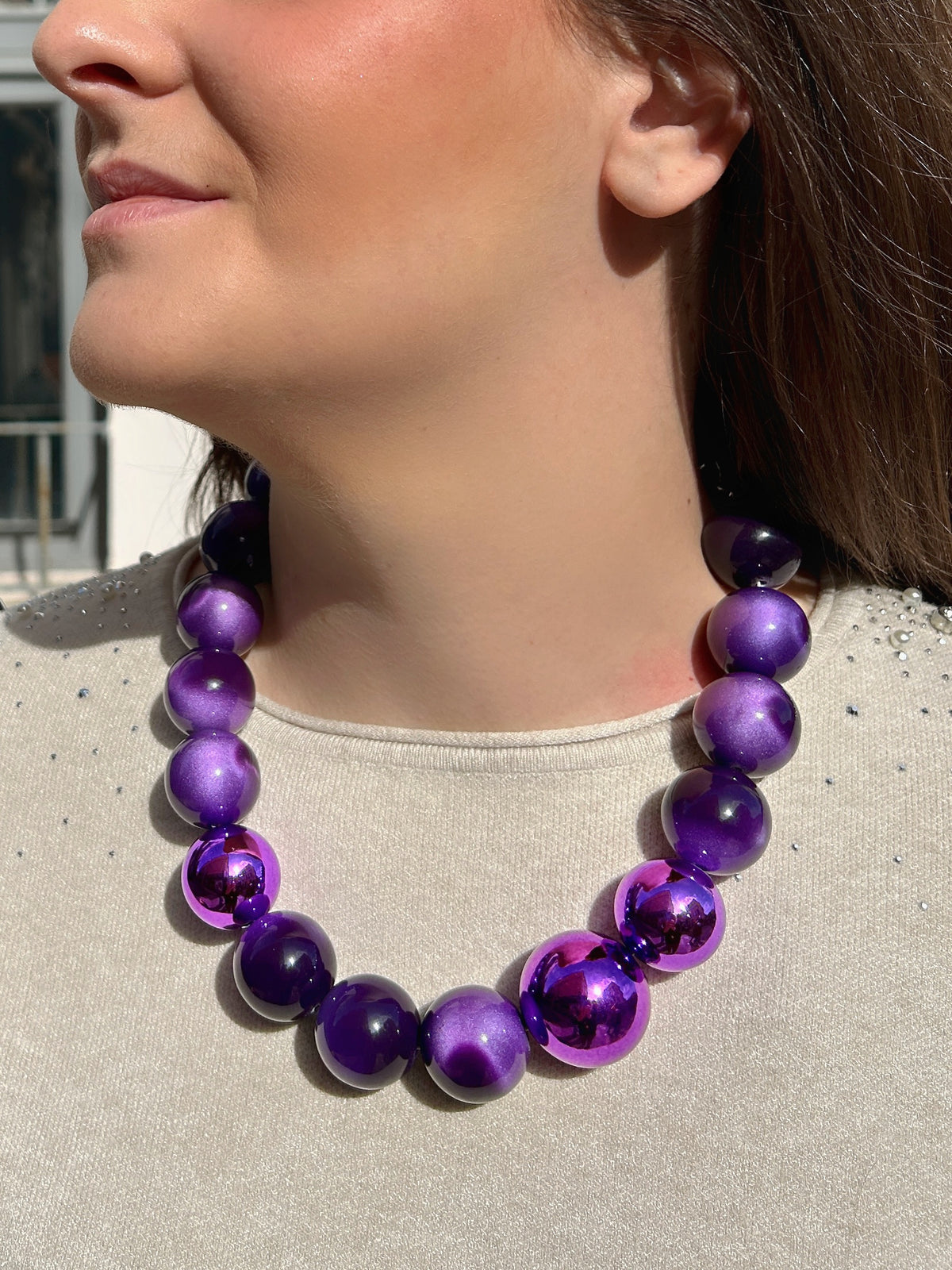 Collier Britney Violet Francine Bramli Paris composé de grosses perles rondes violettes aux effets marbrés, nacrés et métallisés, avec chaîne argentée.