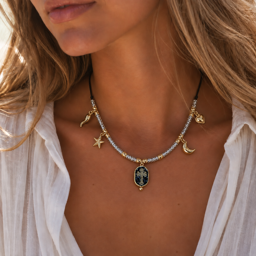 ALT : Collier Palombaggia Croix Noir Amadrina avec médaillon croix dorée sur fond noir pailleté
